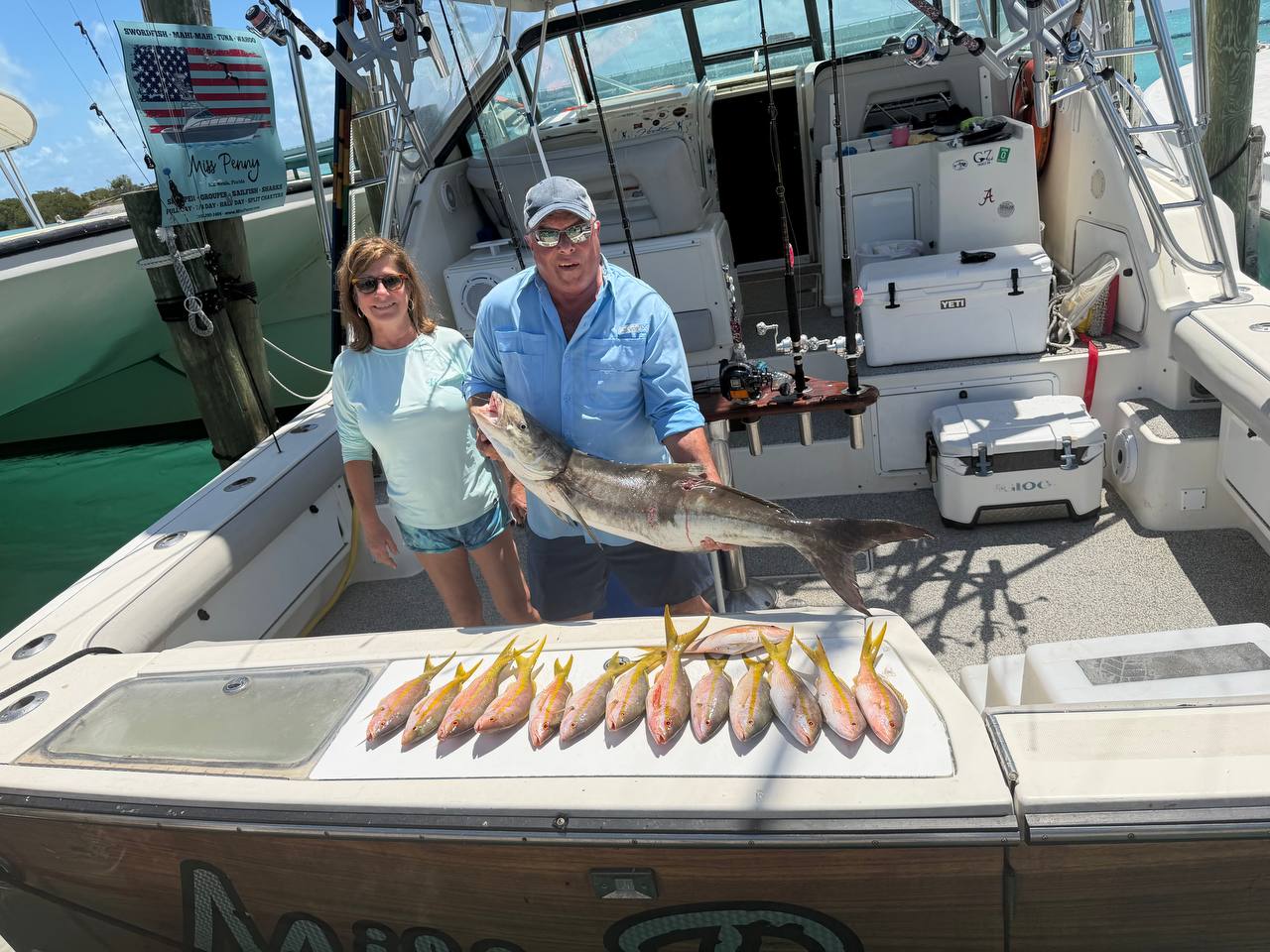 Anglers posing with a keeper cobia and a row of yellowtail snapper aboard Miss Penny at the dock