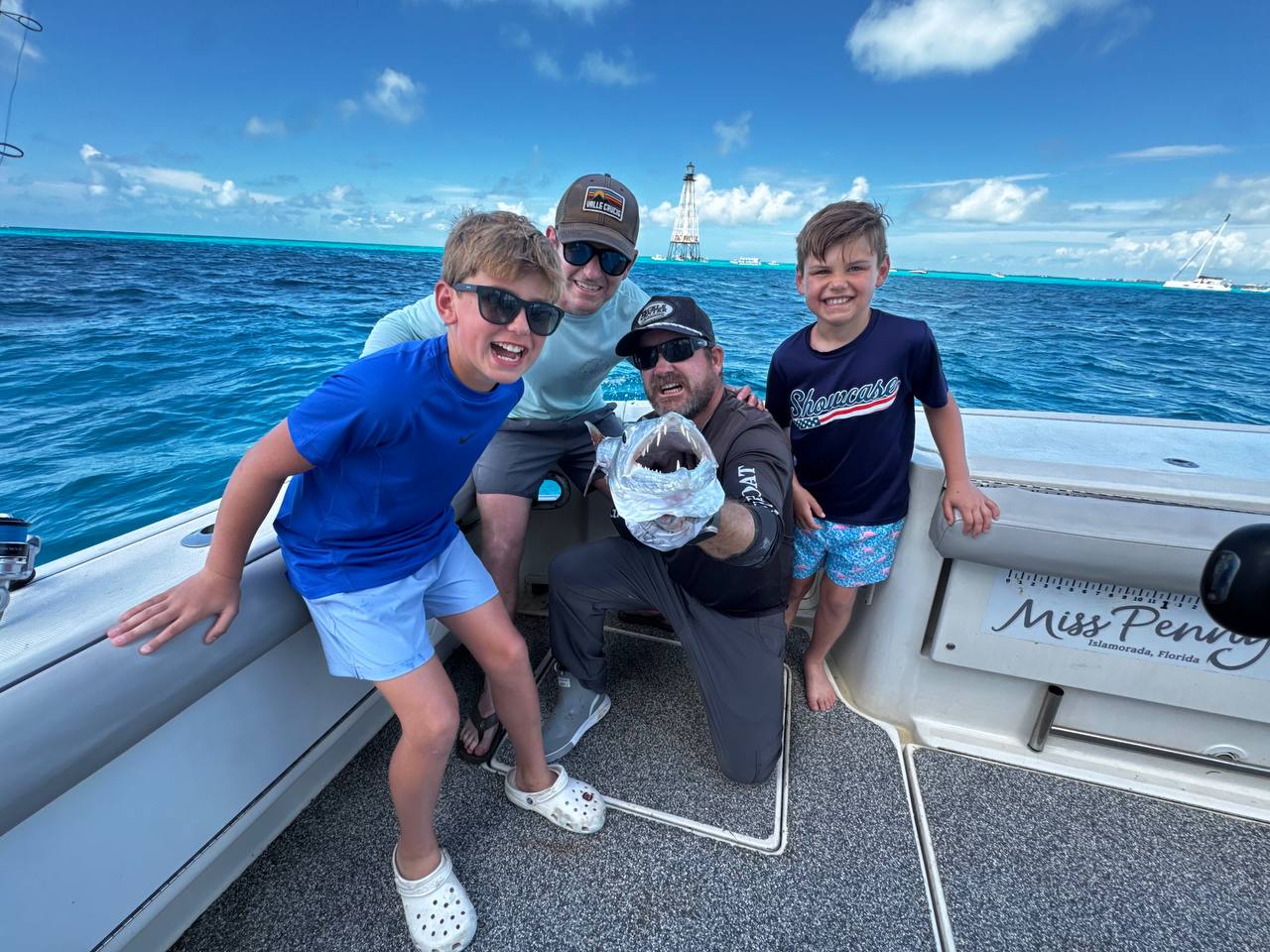 Family aboard Miss Penny showing off a catch during a bright day on the water in Islamorada