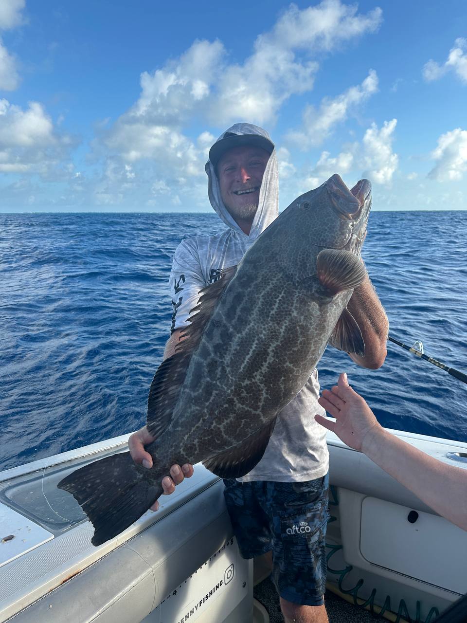 Angler aboard Miss Penny holding a large black grouper during May fishing in Islamorada