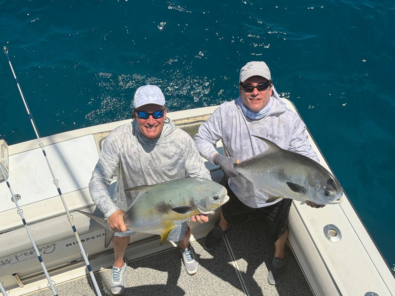 Captain Chad and an angler holding two big permit aboard Miss Penny